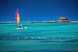 Color catamaran sailboat or winsurf sailing in calm caribbean sea, summer vacation and sport