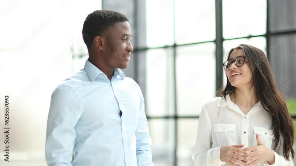 Couple of business people discussing tasks walking in the office hall. Couple of business people discussing tasks walking in the office hall.