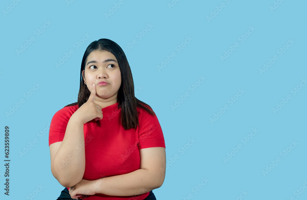 Portrait girl young woman asian chubby fat cute beautiful pretty one person wearing a red shirt is sitting, looking, and thinking idea suspiciously and seriously isolated blue background Portrait girl young woman asian chubby fat cute beautiful pretty one person wearing a red shirt is sitting, looking, and thinking idea suspiciously and seriously isolated blue background