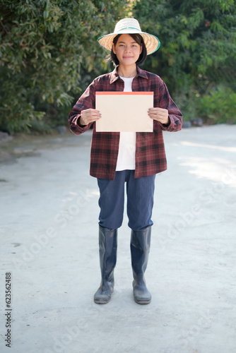 A female farmer in a red shirt standing holding an A4 size paper sign.