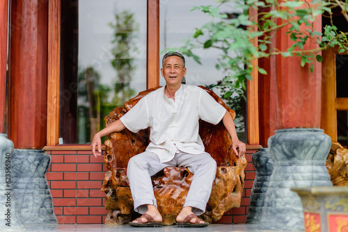 portrait of a old Asian man sit in a wooden chair © Minh