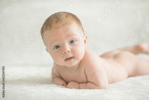 Baby boy crawling on bed. Little child playing in white sunny bedroom. Infant kid learning to crawl. Nursery for children. Textile, clothing and bedding for kids. Family morning at home.