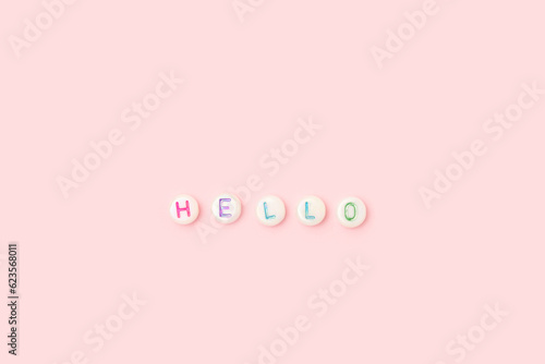 Word Hello. Quote made of white round beads with multicolored letters on a pink background. © rorygezfresh