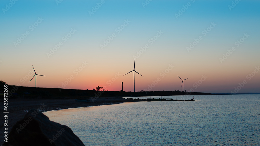 Wind farms on sea coast at dawn. Windmill power. Sunrise seascape Wind farms on sea coast at dawn. Windmill power. Sunrise seascape