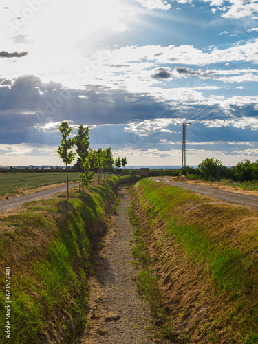 Dry irrigation canal with storm clouds in the sky. Drought-induced water shortage."