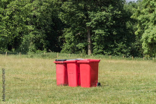 A row of red bins on the grass in a park, environment, and object concept illustration.