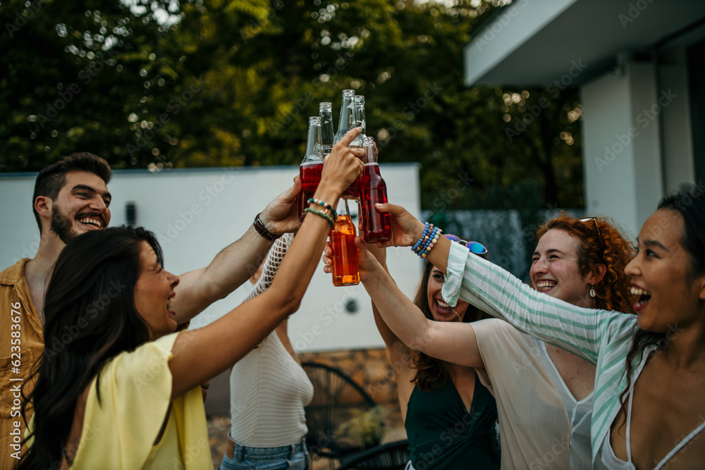 They raise their cocktail bottles in a toast, clinking them together, and celebrating the start of the party