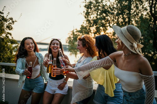 Multiethnic female friends make a reunion at the house balcony, toasting and having fun © La Famiglia