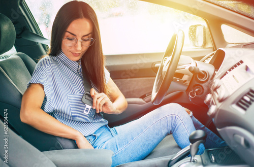 Safety and car driving concept. Close up photo of smiling young woman driver while she fastening seat belt. © My Ocean studio
