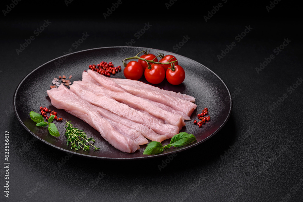 Raw chicken or turkey fillet cut into strips with spices and herbs Raw chicken or turkey fillet cut into strips with spices and herbs