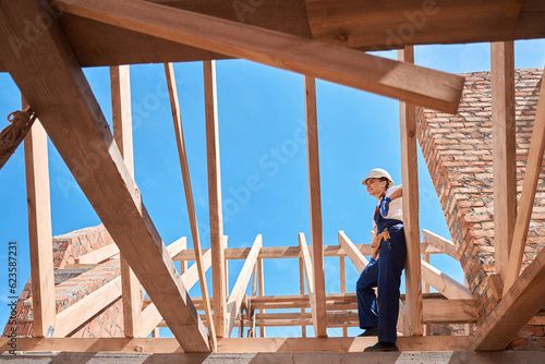 Forewoman climbing up on wooden roof frame to look at construction site