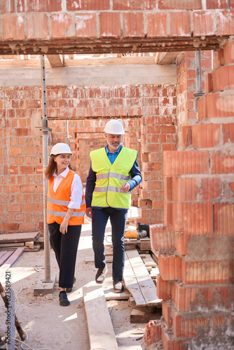 Building inspectors in hardhats and hi vis vests walking along construction site © Viacheslav Yakobchuk