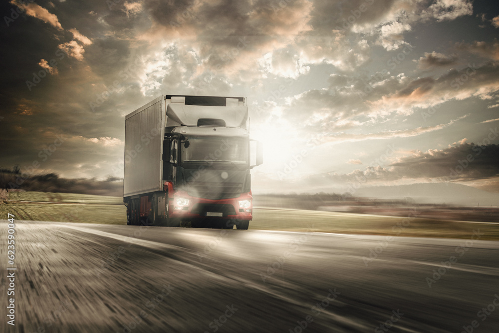 beladener lkw schnell unterwegs auf autobahn mit licht bei stahlender sonne und düsterem himmel beladener lkw schnell unterwegs auf autobahn mit licht bei stahlender sonne und düsterem himmel
