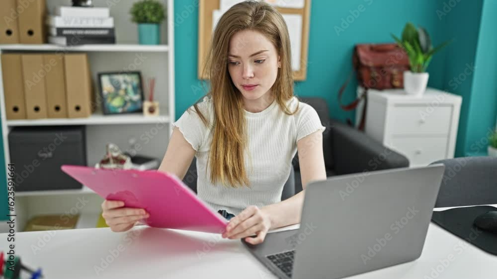 Young blonde woman business worker using laptop reading document at the office Young blonde woman business worker using laptop reading document at the office