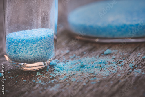 blue copper sulphate granules in glass floors - insulated close-up on wood background photo