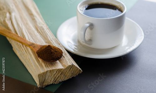 cup of spresso, with freshly ground aromatic coffee and a wooden spoon with coffee powder, on a piece of wood colored background photo