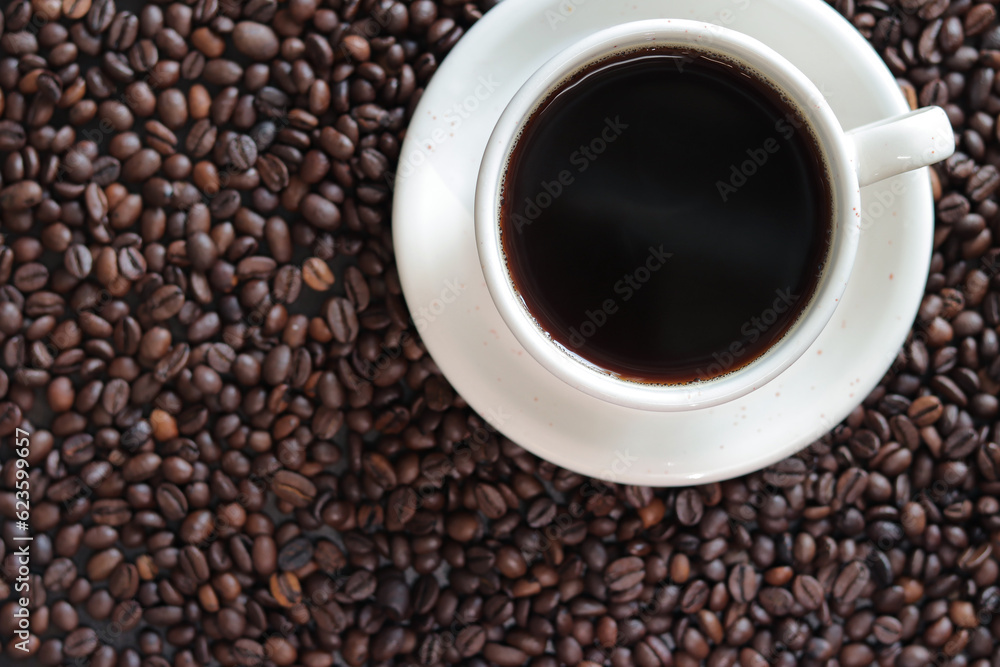 Top view of a cup of coffee on the background of roasted coffee beans. Background of freshly roasted coffee beans with a cup of hot coffee, copy space Top view of a cup of coffee on the background of roasted coffee beans. Background of freshly roasted coffee beans with a cup of hot coffee, copy space