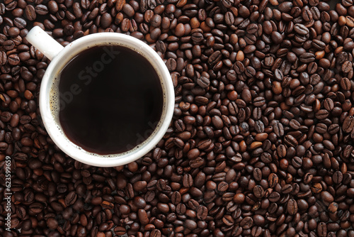 Top view of a cup of coffee on the background of roasted coffee beans. Background of freshly roasted coffee beans with a cup of hot coffee  copy space