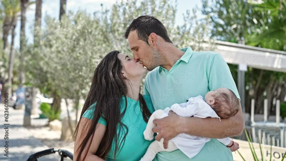 Family of three standing together kissing at street