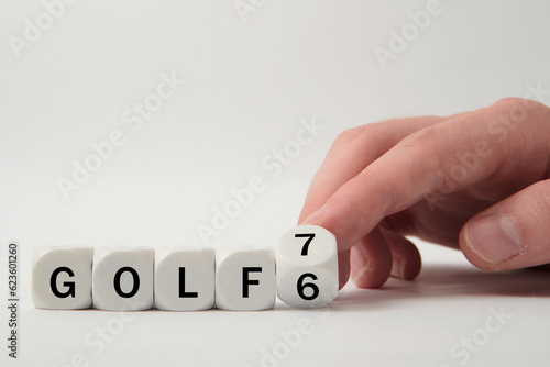 Hand turns dice and changes the expression "Golf 6" to "Golf 7" on white background 