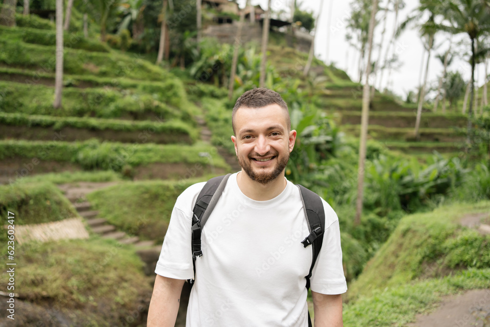 Male tourist with a backpack walking on the rice field. Male tourist with a backpack walking on the rice field.