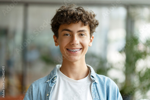 Closeup portrait of smiling smart curly haired school boy wearing braces on teeth looking at camera. Education concept  photo