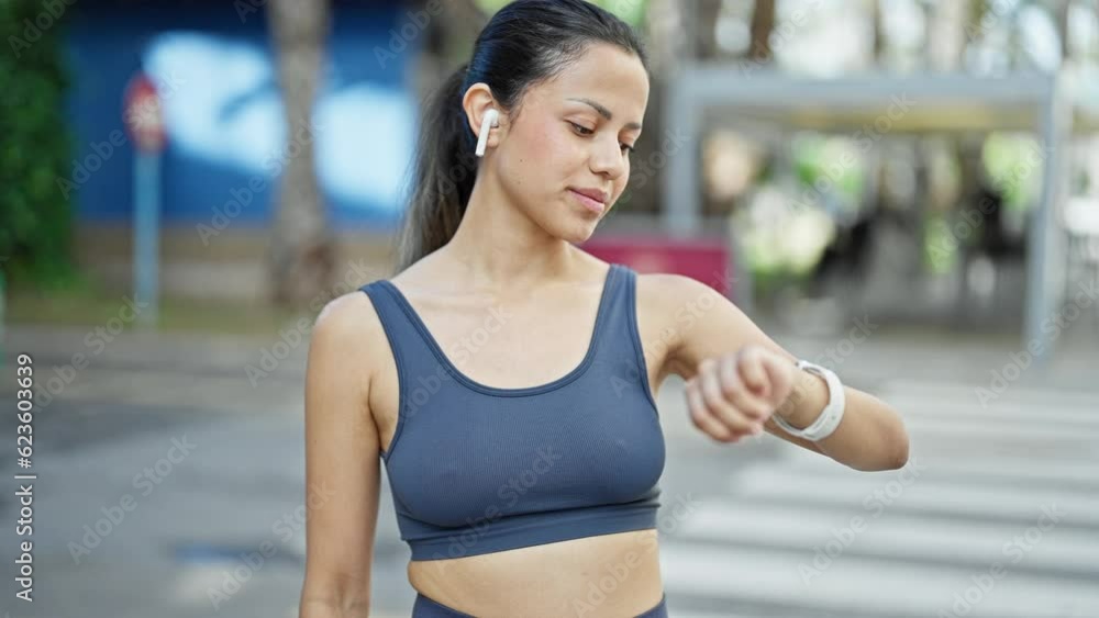 Young beautiful hispanic woman wearing sportswear looking stopwatch at street Young beautiful hispanic woman wearing sportswear looking stopwatch at street