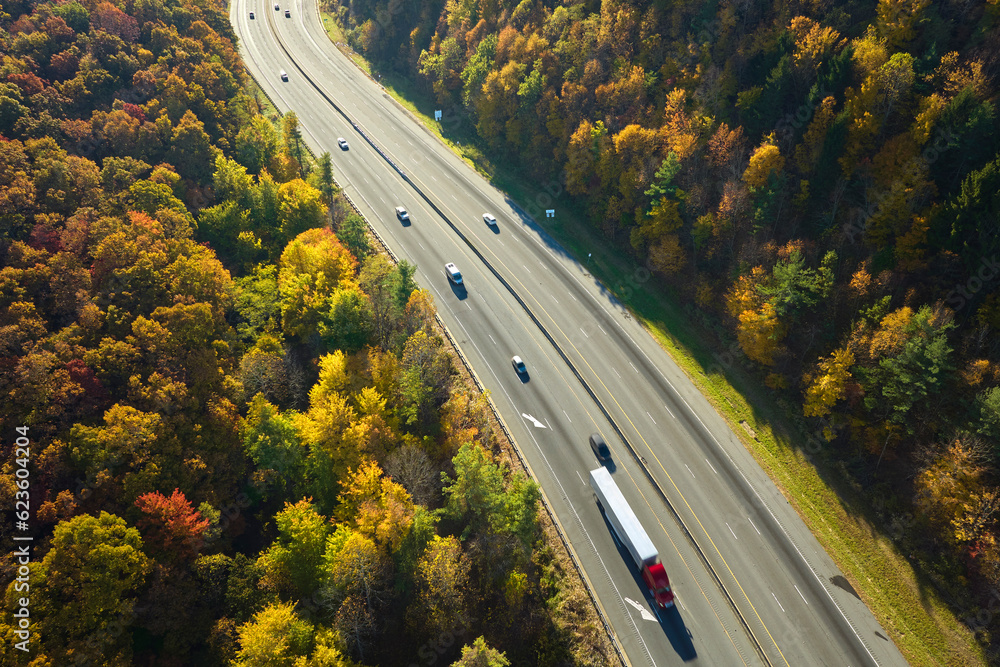 I-40 freeway road leading to Asheville in North Carolina over Appalachian mountain pass with yellow fall forest and fast moving trucks and cars. Concept of high speed interstate transportation