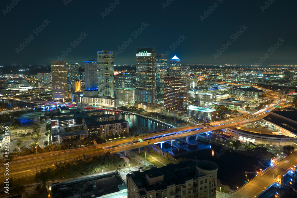 View from above of brightly illuminated high skyscraper buildings and moving traffic in downtown district of Tampa city in Florida, USA. American megapolis with business financial district at night