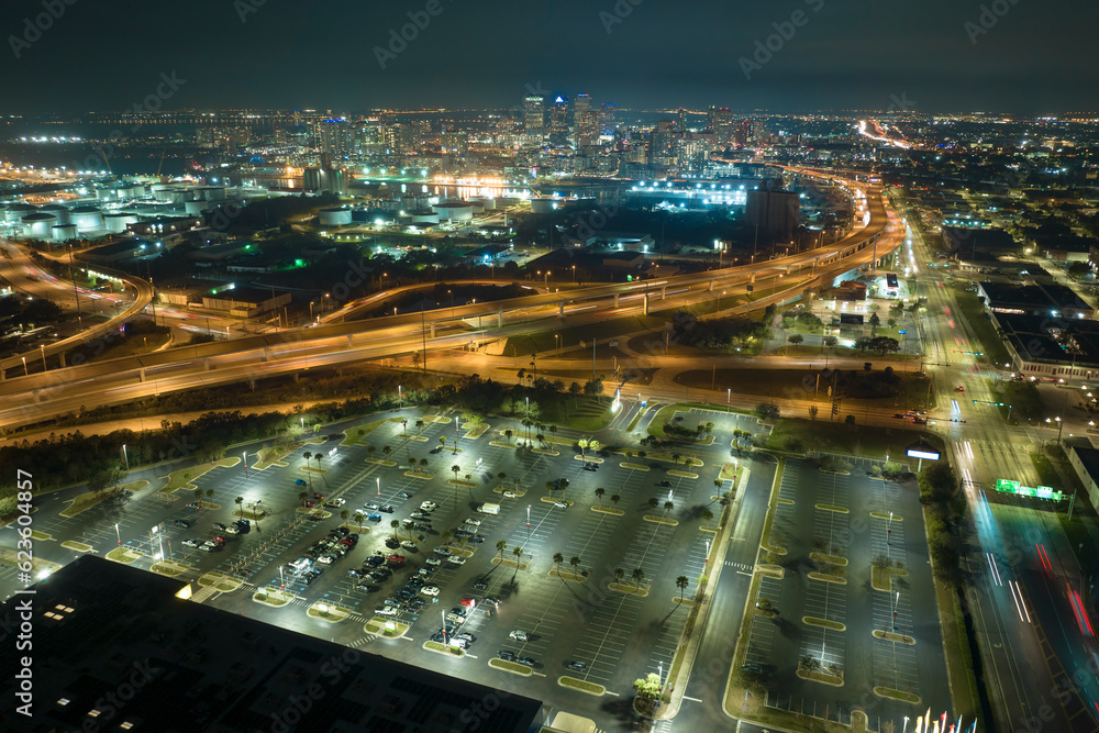 View from above of many parked cars on illuminaded parking lot at night in front of a superstore. Place for vehicles in front of a shopping mall center