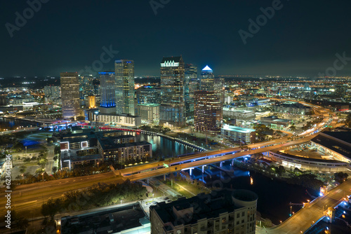 View from above of brightly illuminated high skyscraper buildings and moving traffic in downtown district of Tampa city in Florida, USA. American megapolis with business financial district at night