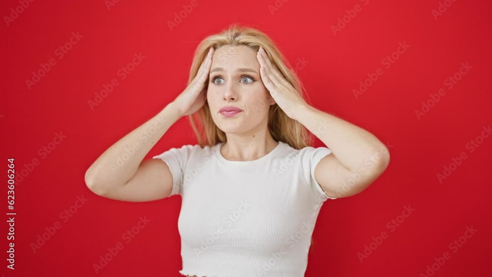 Young blonde woman doing surprise gesture over isolated red background Young blonde woman doing surprise gesture over isolated red background