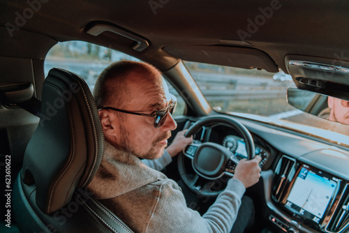 A man with a sunglasses driving a car at sunset. The concept of car travel