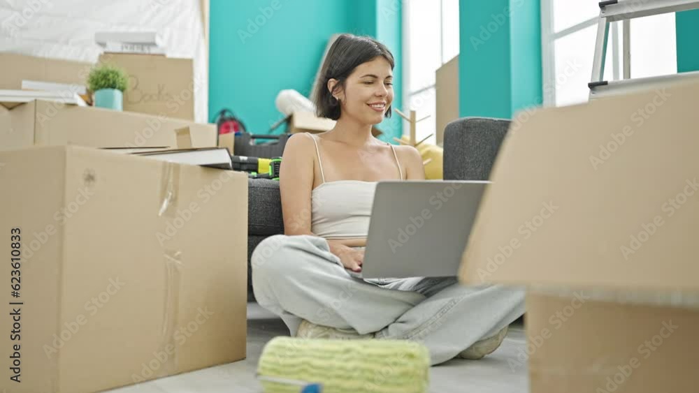 Young beautiful hispanic woman using laptop sitting on floor at new home Young beautiful hispanic woman using laptop sitting on floor at new home