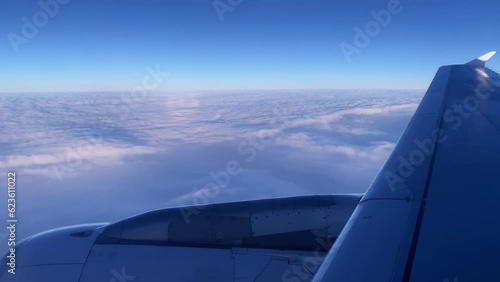 view from window on airplane turbine of plane while flying above clouds, beautiful colorful dramatic sky with cloudscape, transportation air passengers, heavenly space, abode God, meditative calmness photo