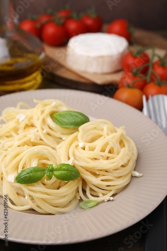 Delicious pasta with brie cheese and basil leaves on table, closeup