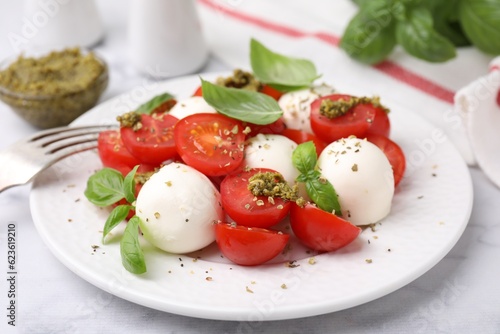 Tasty salad Caprese with tomatoes, mozzarella balls and basil on white table, closeup