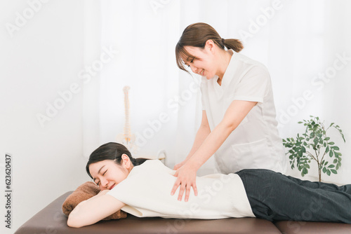 整骨院で腰を揉む整体師・マッサージ師・セラピストの女性（腰痛） 