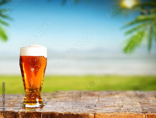 big glass of beer on a table with beach background