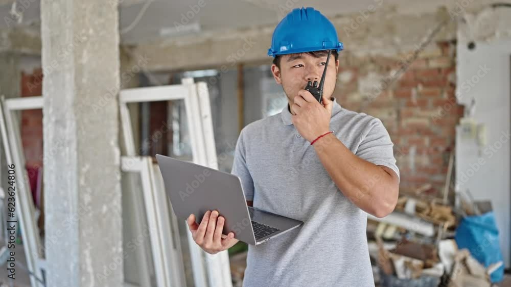 architect using laptop speaking on walkie talkie at construction site architect using laptop speaking on walkie talkie at construction site