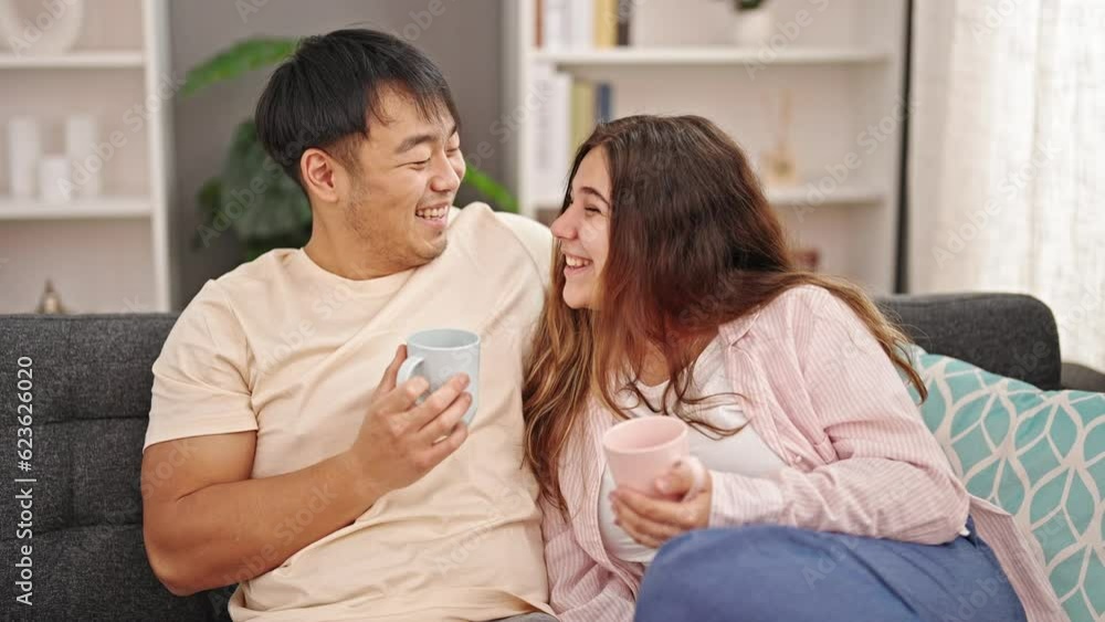 Man and woman couple sitting on sofa drinking coffee at home Man and woman couple sitting on sofa drinking coffee at home