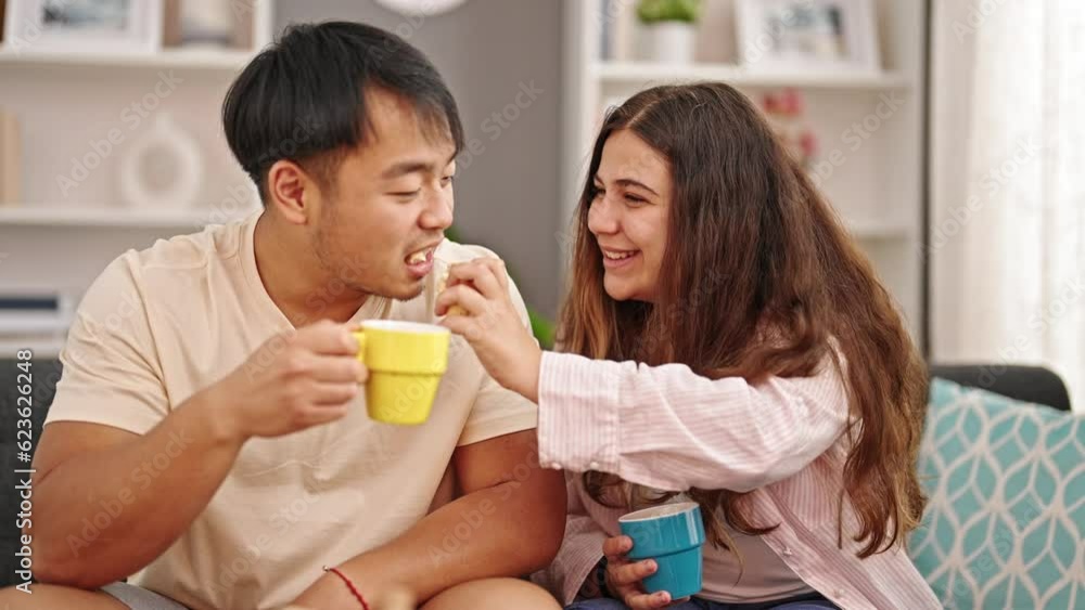 Man and woman couple sitting on sofa having breakfast at home Man and woman couple sitting on sofa having breakfast at home