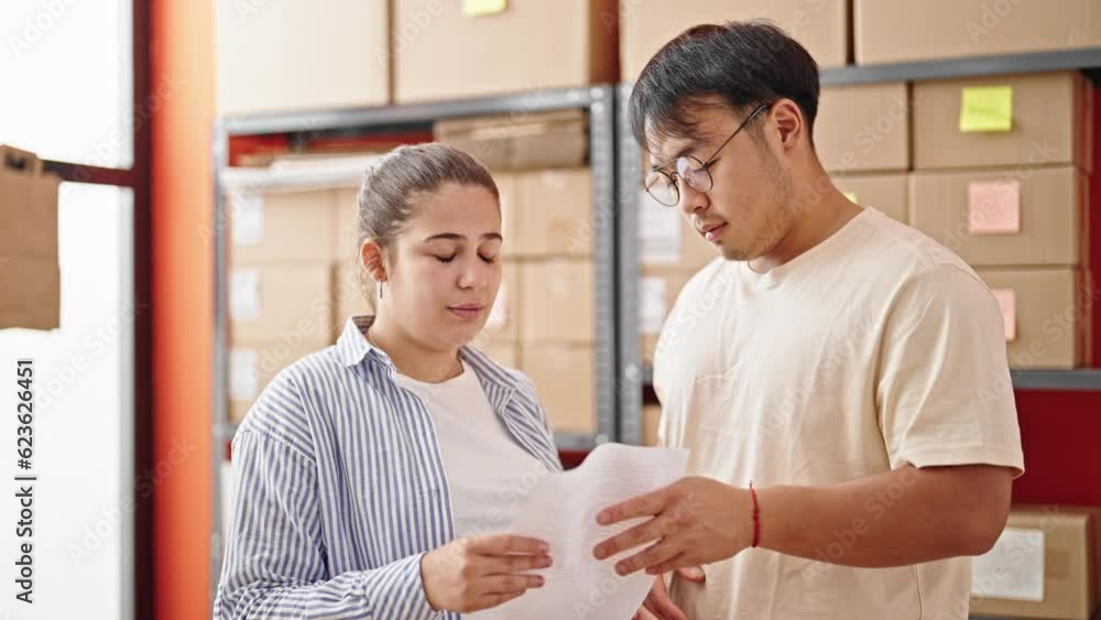 Man and woman ecommerce business workers reading document with serious expression at office Man and woman ecommerce business workers reading document with serious expression at office