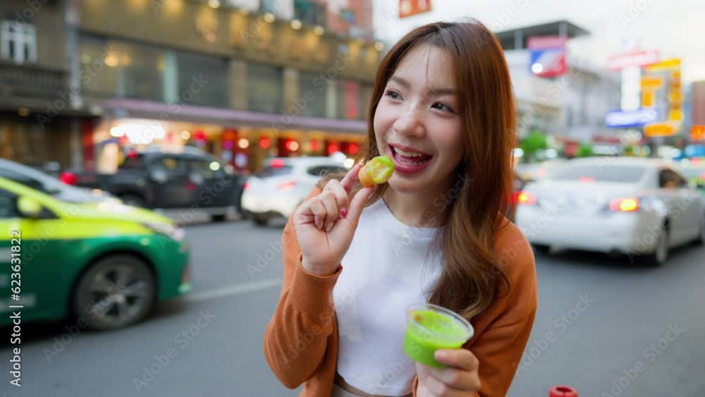 Young Asian tourists standing and eating Thai desserts. Young beautiful tourists in Chinatown street food market, Bangkok, Thailand Young Asian tourists standing and eating Thai desserts. Young beautiful tourists in Chinatown street food market, Bangkok, Thailand