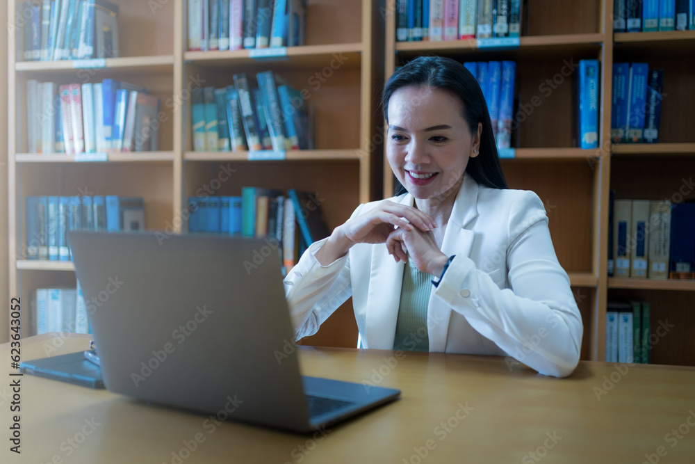 Fototapeta premium University teacher giving online consulting student via laptop in library