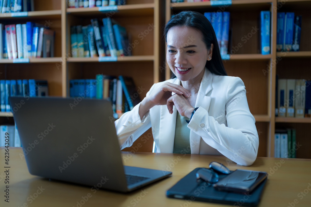 University teacher giving online consulting student via laptop in library University teacher giving online consulting student via laptop in library