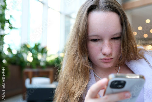 Foto young girl with freckles a European woman sits with a phone in her hands in the lobby of a hotel