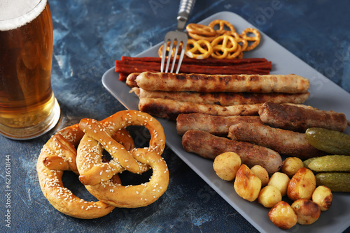 Plate with different snacks on blue background. Oktoberfest celebration photo