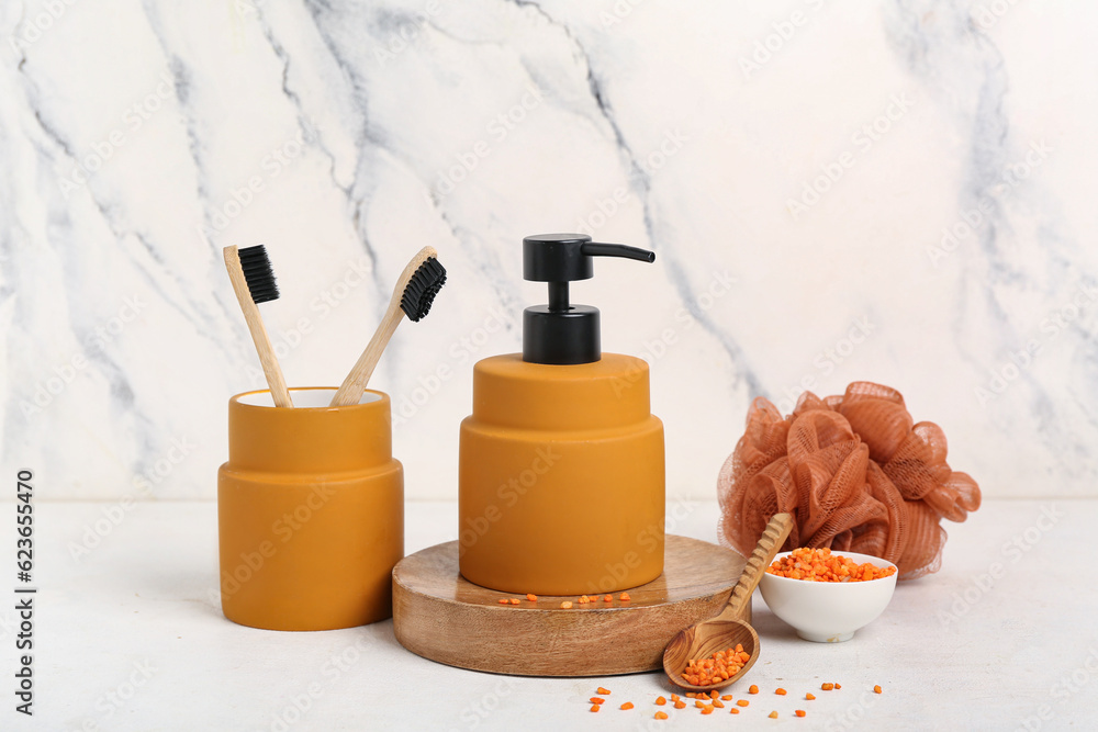 Bottle of cosmetic product, toothbrushes, bath sponge and sea salt on light background Bottle of cosmetic product, toothbrushes, bath sponge and sea salt on light background