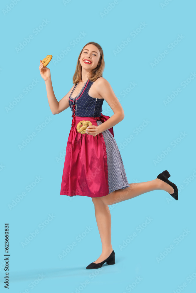 Beautiful Octoberfest waitress with pretzels dancing on blue background Beautiful Octoberfest waitress with pretzels dancing on blue background